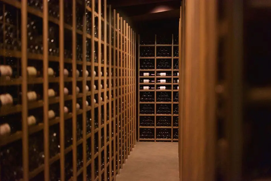 Dimly lit wine cellar with wooden racks filled with wine bottles on both sides