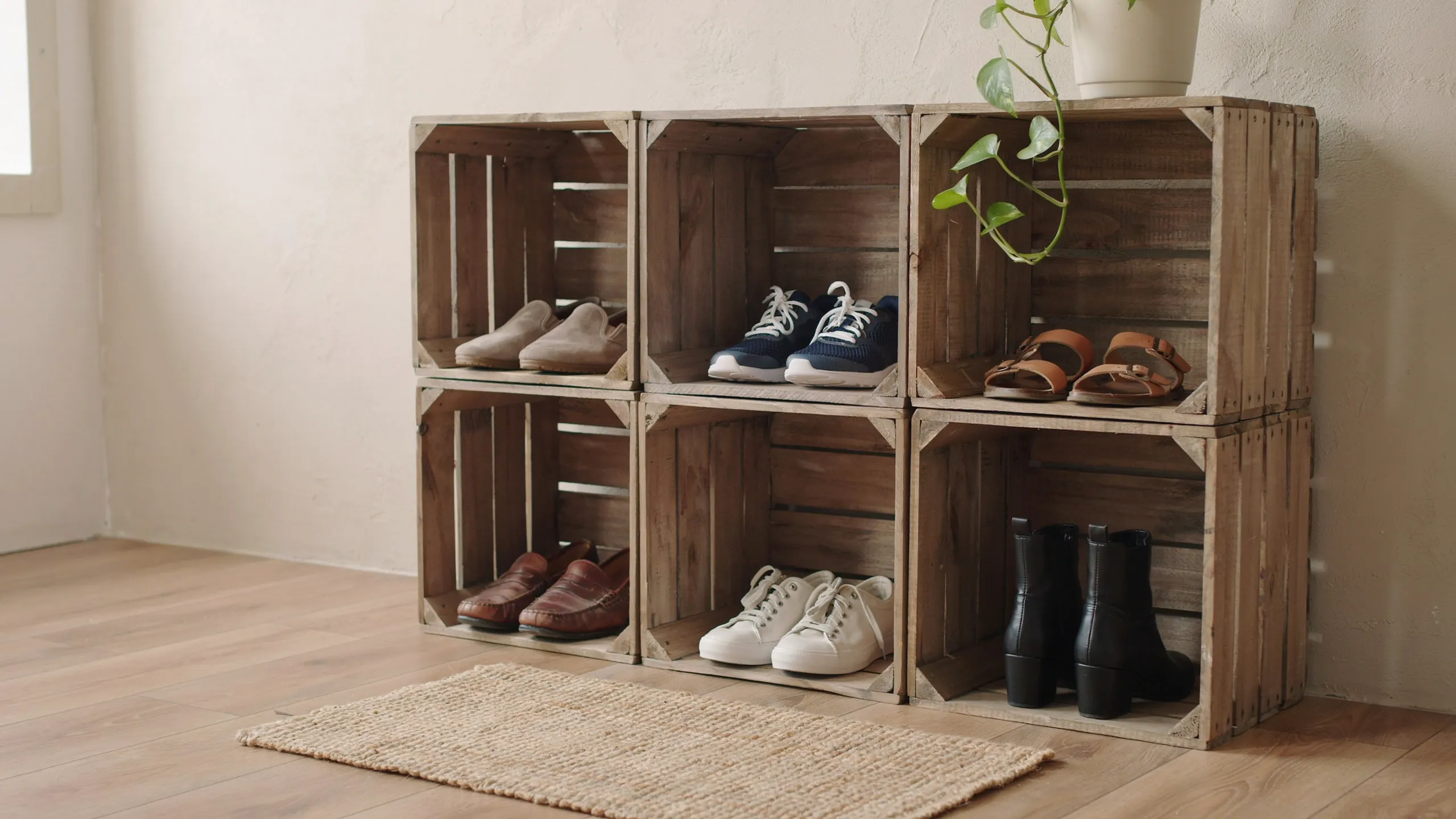 Wooden crates stacked to organize various shoes, including loafers, sneakers, sandals, and boots.