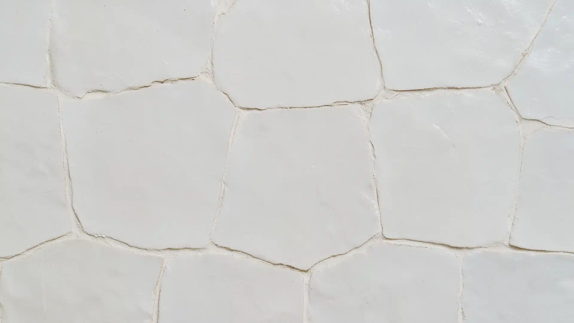Close-up of handmade white Zellige tiles with irregular edges and matching white grout