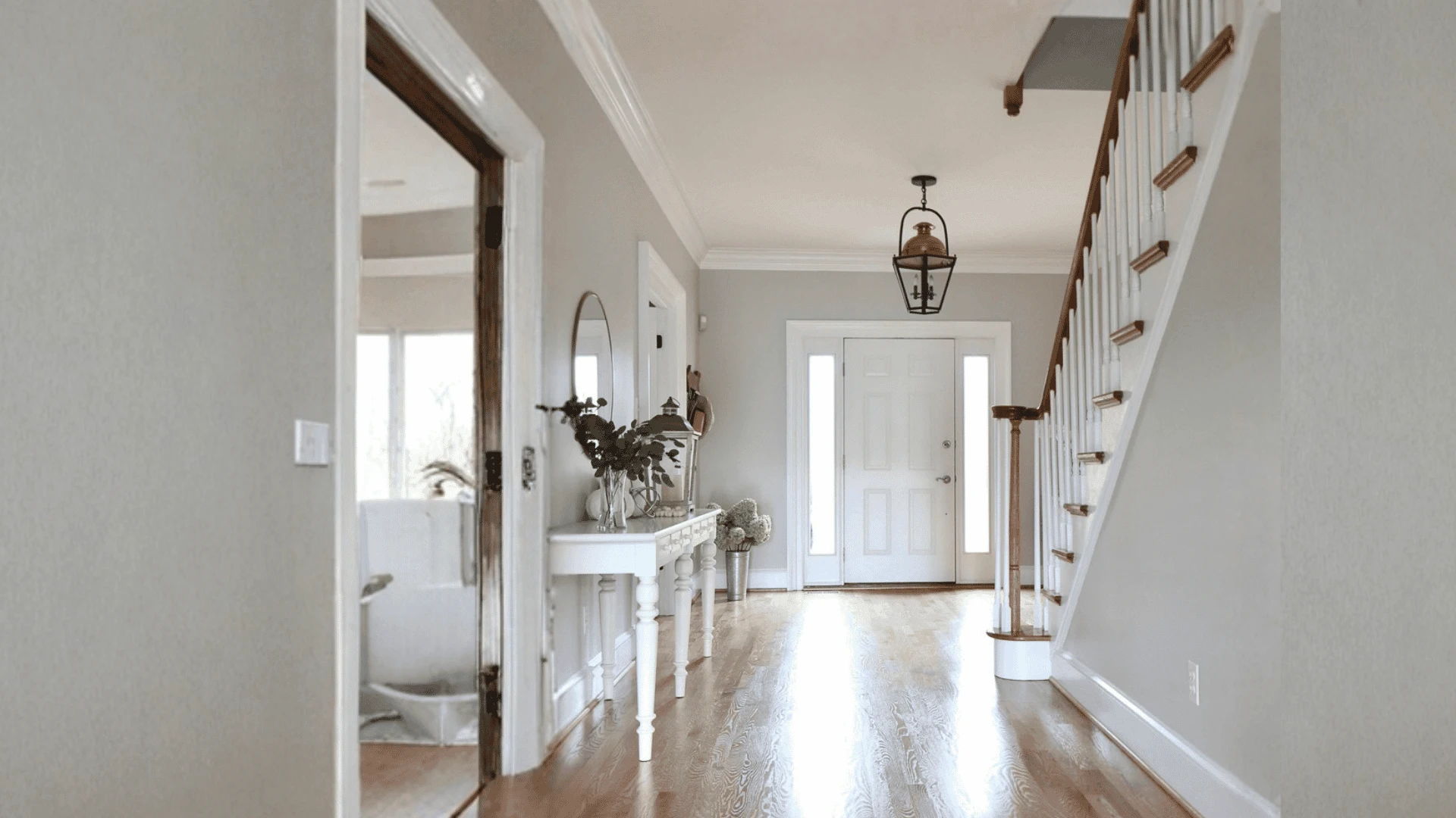 Bright entryway with light taupe walls, hardwood floors, and a staircase.