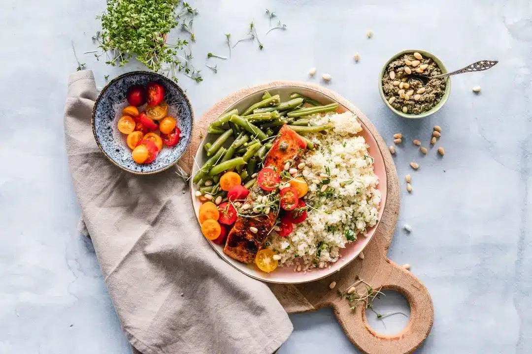 Salmon fillet with quinoa, tomatoes, and green beans on wooden board with side dishes