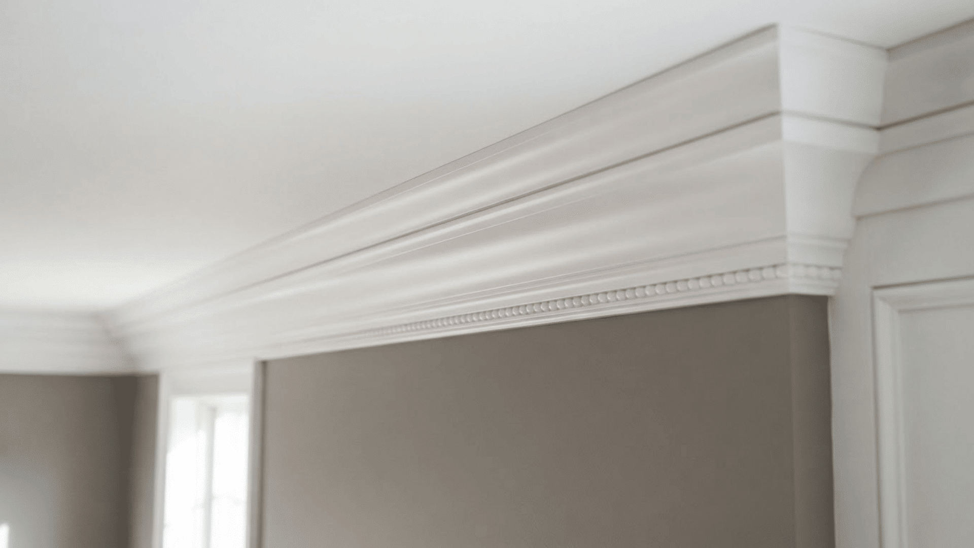 built-up crown molding with layered white trim framing the top of a neutral interior wall