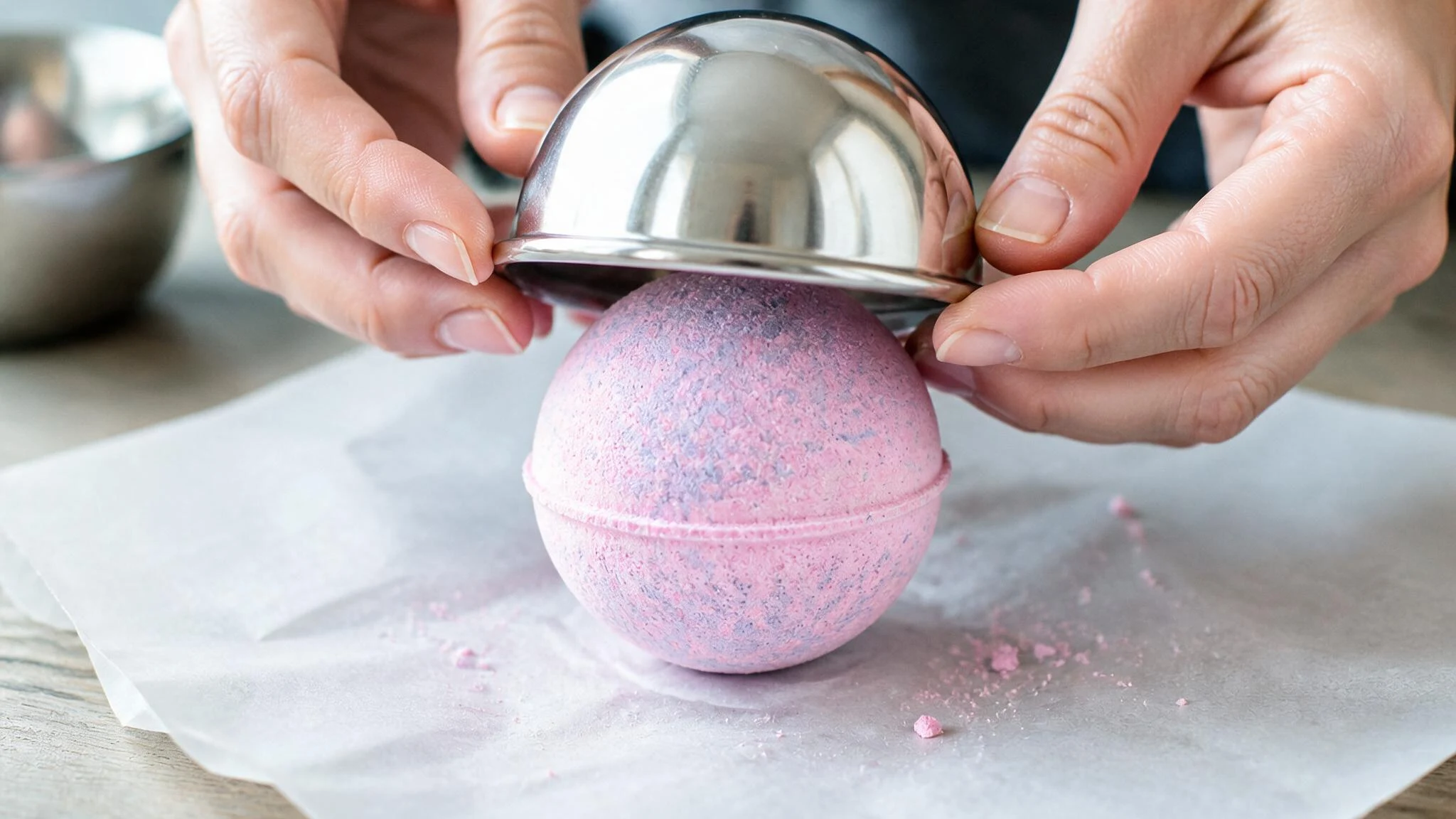 Carefully removing a round bath bomb from a metal mold