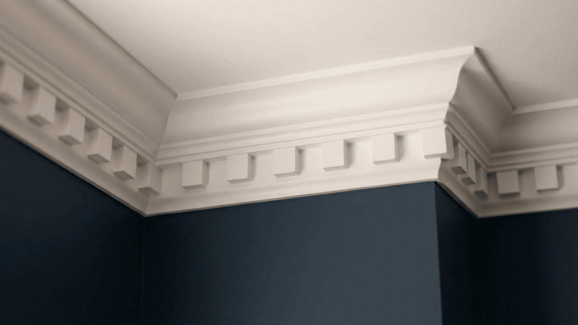 dentil crown molding with repeating square blocks above dark blue walls and white ceiling