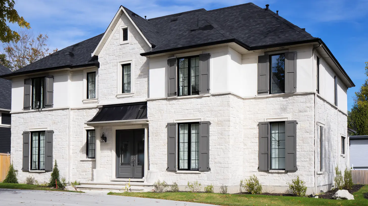 French Provincial house with white stone exterior dark shutters symmetrical windows and gray roof