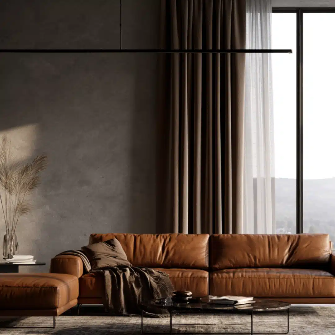 Grey living room with a warm camel leather sofa, dark accents, and soft natural light.