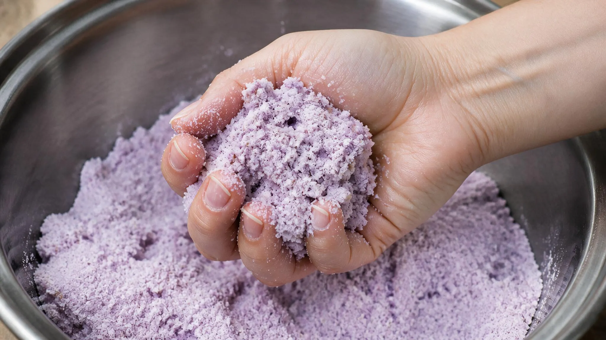 Hand squeezing bath bomb mixture to check its damp sand texture
