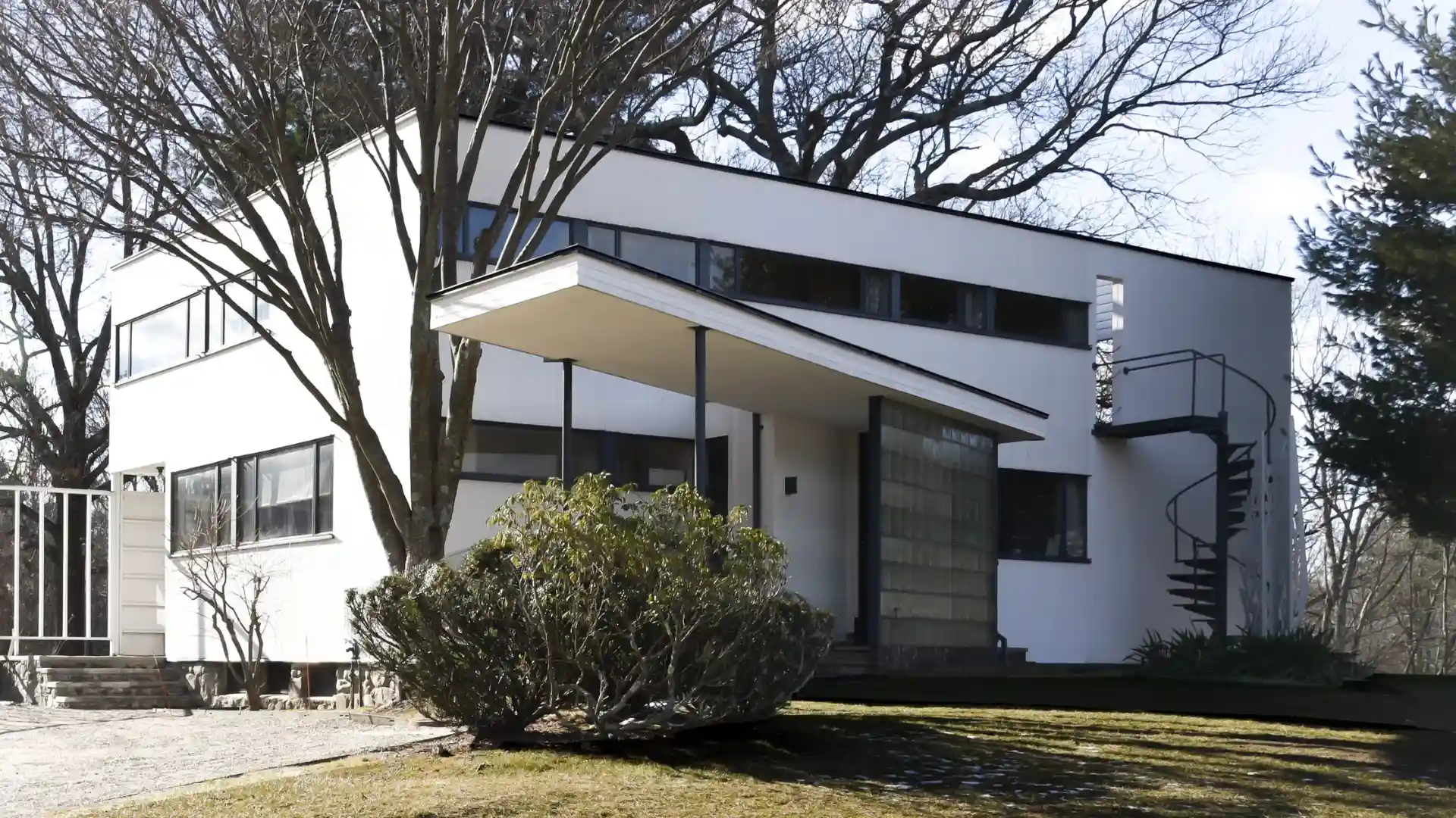 Modern mid century home with clean geometric lines large windows and a landscaped front yard