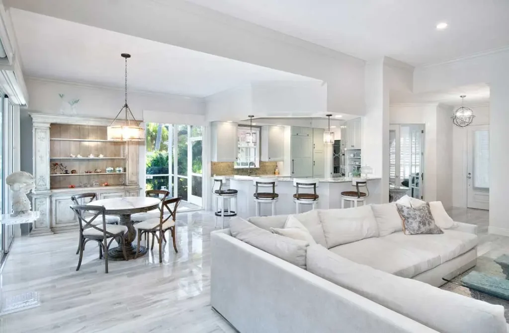 Spacious open-plan living room and kitchen with white furniture and wooden dining table