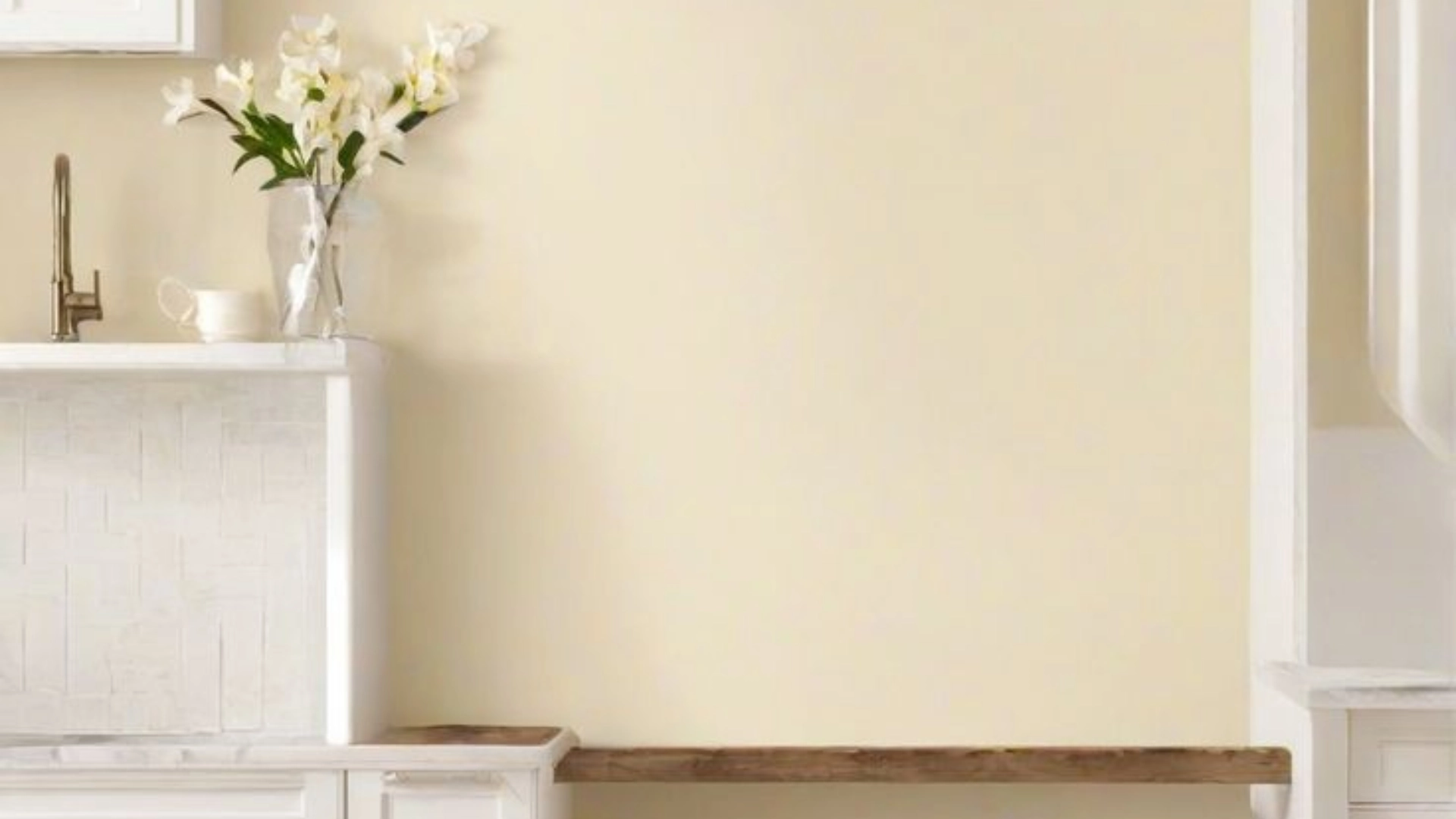 Soft beige wall with white tiles, a wooden shelf, and fresh white flowers