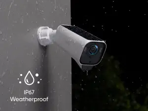 White security camera mounted on exterior wall in rain under dark sky