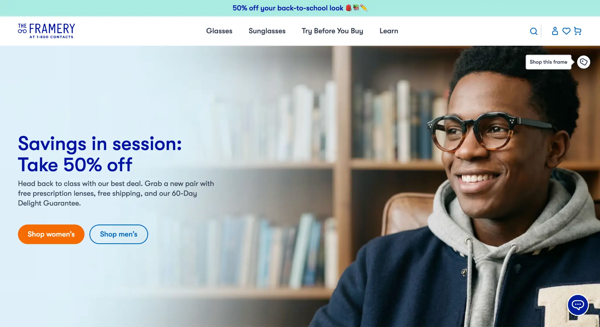 Smiling person wearing glasses and navy jacket with books on wooden shelves in the background