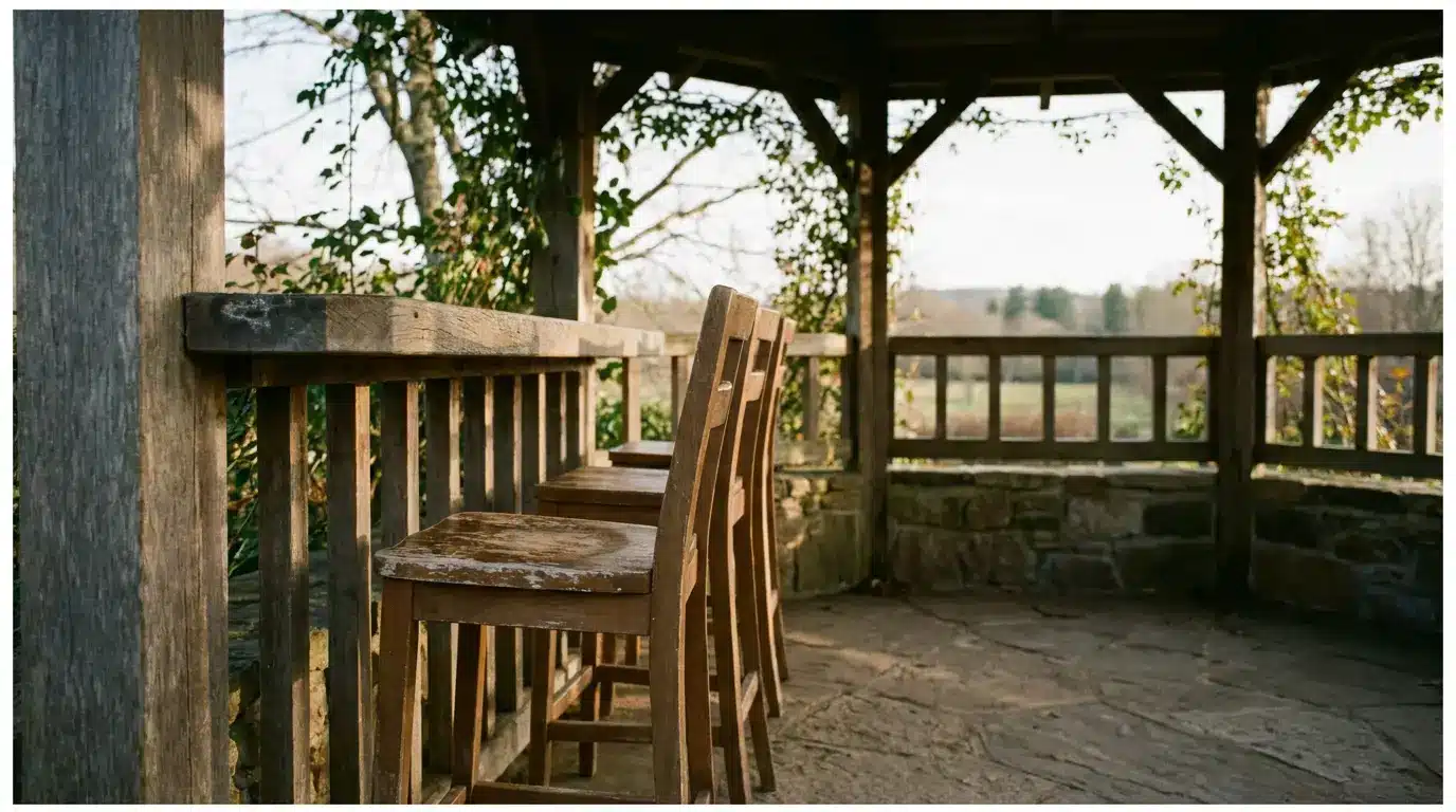 Wooden chairs lined up inside rustic gazebo overlooking scenic countryside landscape