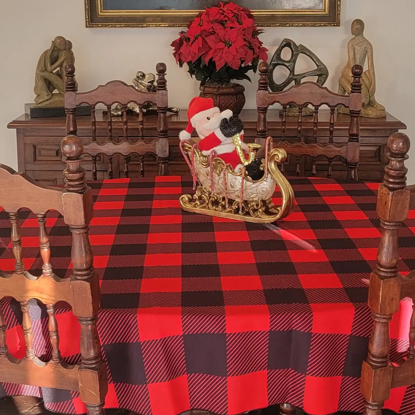 Santa figurine in sleigh centerpiece on red and black plaid tablecloth in dining room