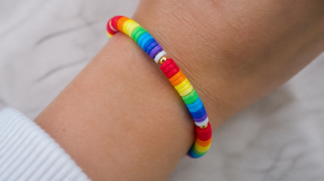 A colorful rainbow clay bead bracelet worn on a person's wrist, showcasing vibrant hues and a playful design.