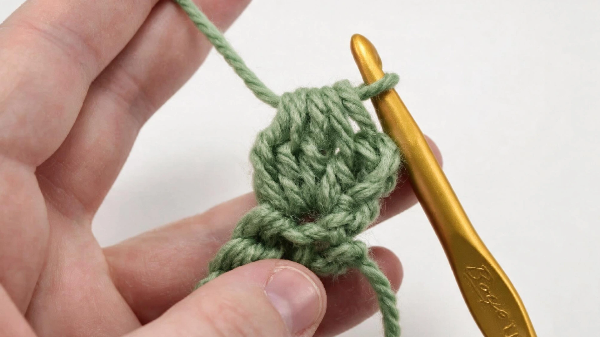 Completed green bobble stitch formed after pulling through the loops with the hook ready to continue.