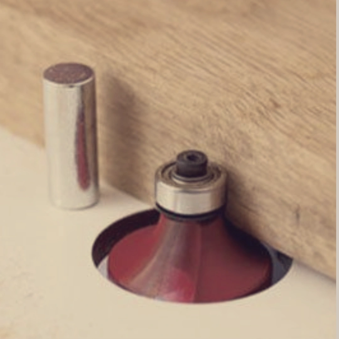 Freehand routing on a router table using a starter pin and bearing-guided bit to safely guide and shape the edge of a wood board.