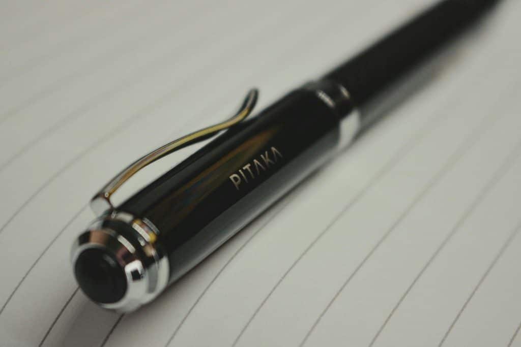 Black pen resting on lined paper in close-up shot