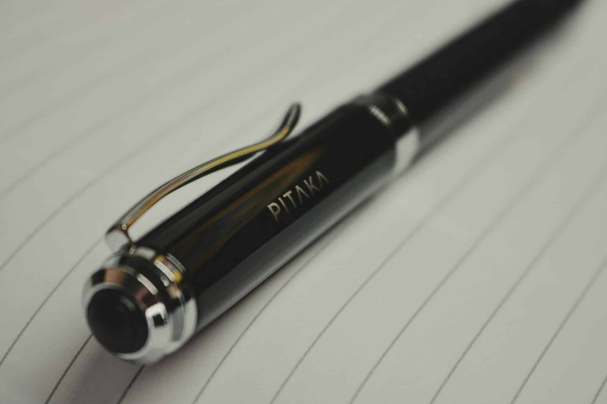Black pen resting on lined paper in close-up shot