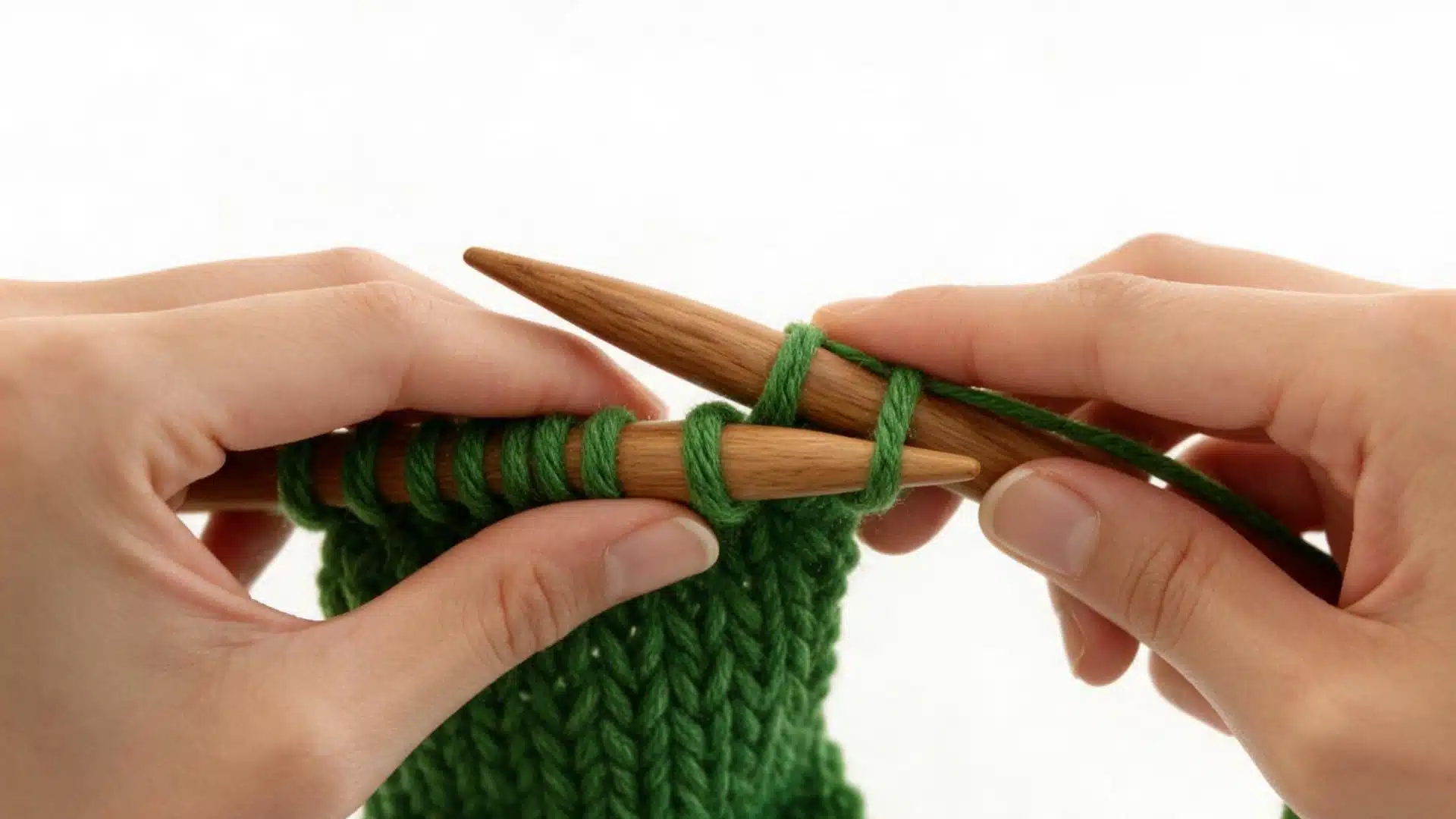 Left needle lifting the first green stitch from the right needle during the bind off process.