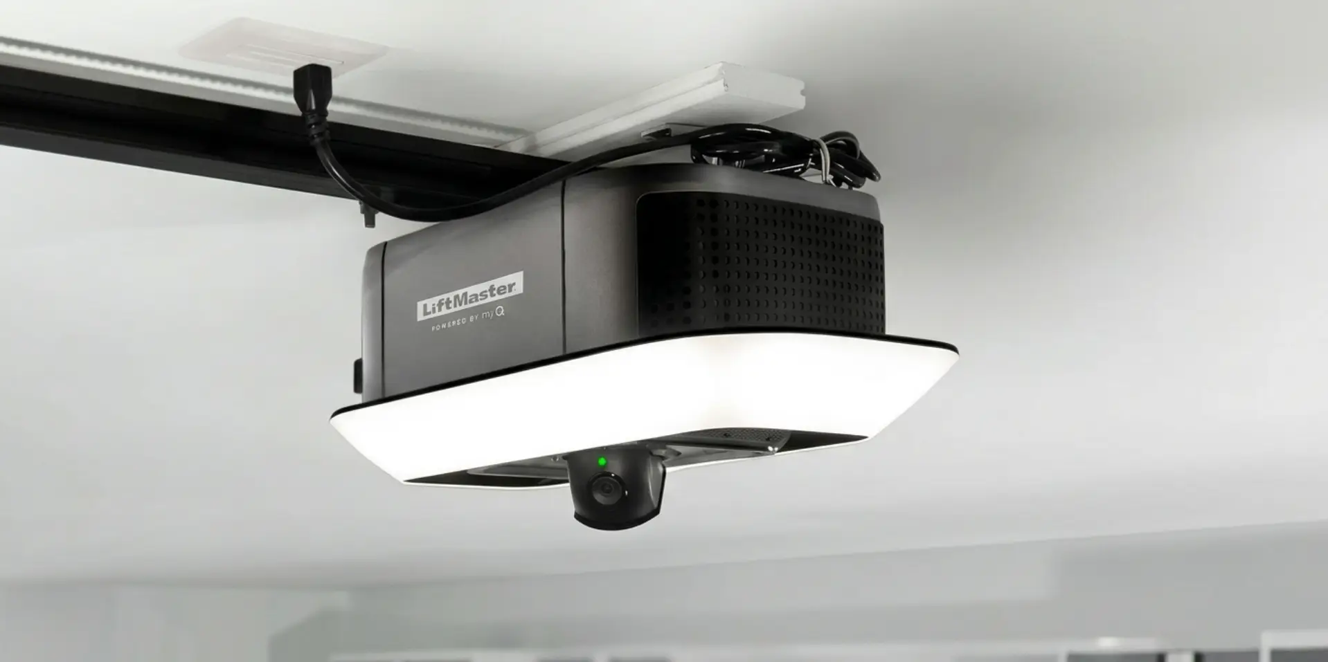 Ceiling-mounted black and white garage door opener with attached camera in a garage setting