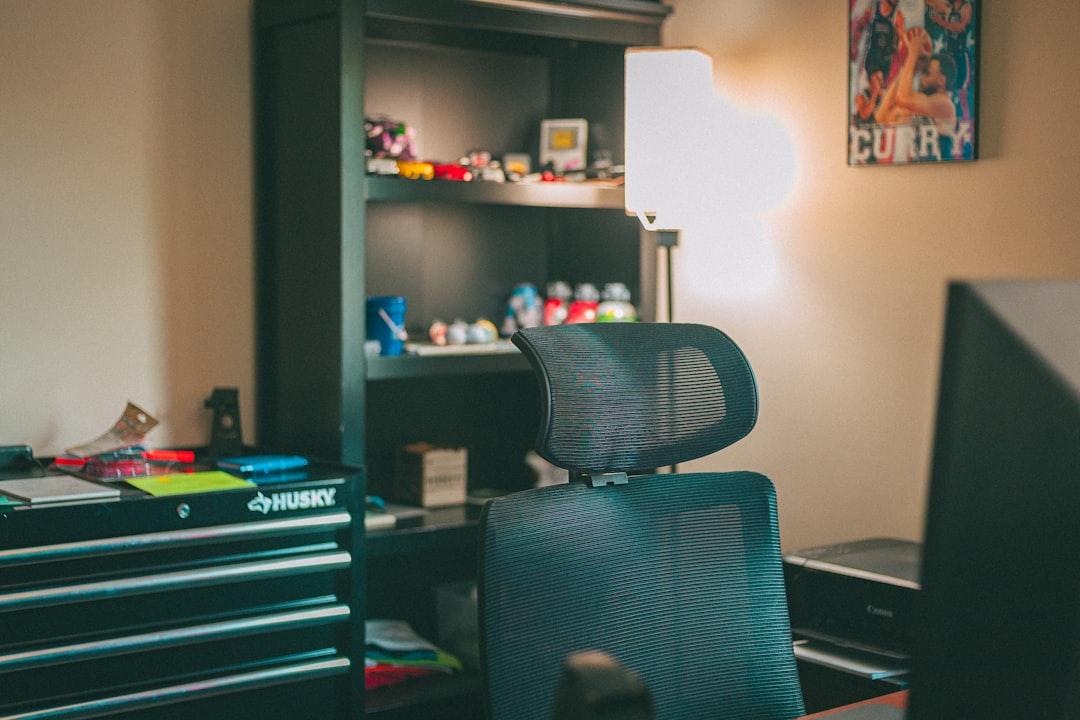 Mesh office chair in home office with shelves and lamp under warm lighting