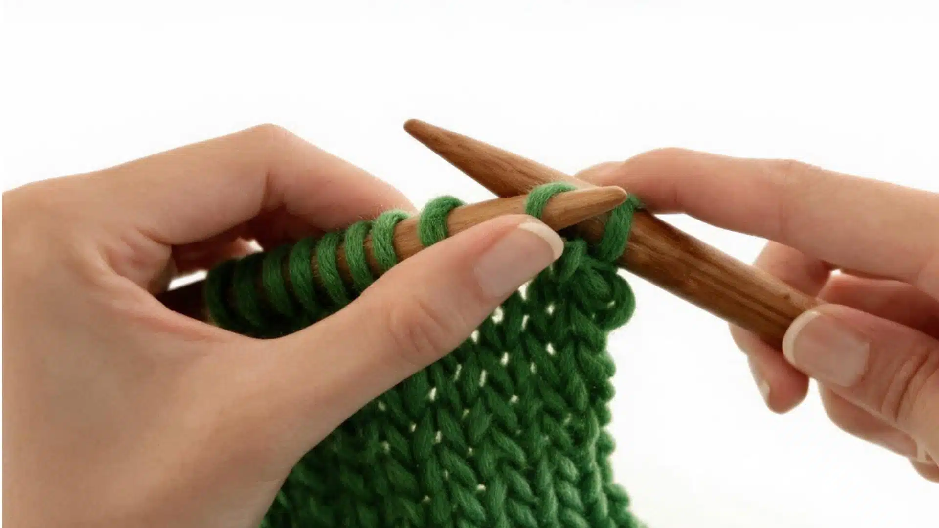 First green stitch being passed over the second stitch with wooden knitting needles.