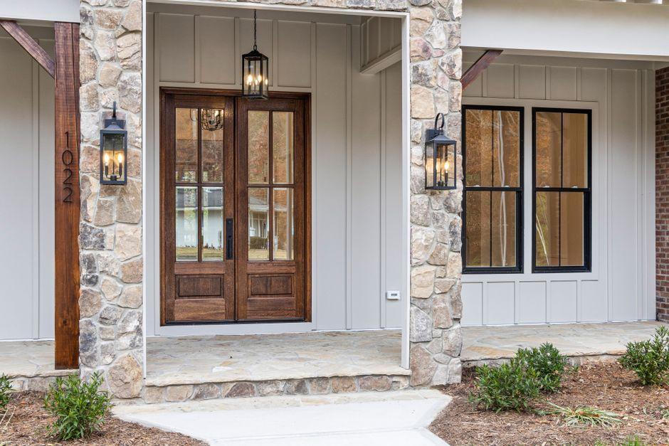 Stone entrance with wooden double doors and lanterns in suburban home exterior