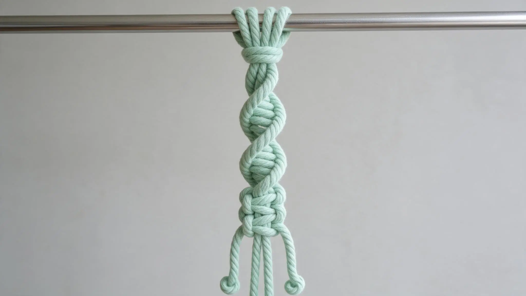 Spiral knot tied with white rope hanging from a wooden dowel