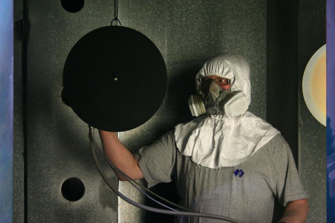Person wearing protective gear holding large black disc in industrial setting