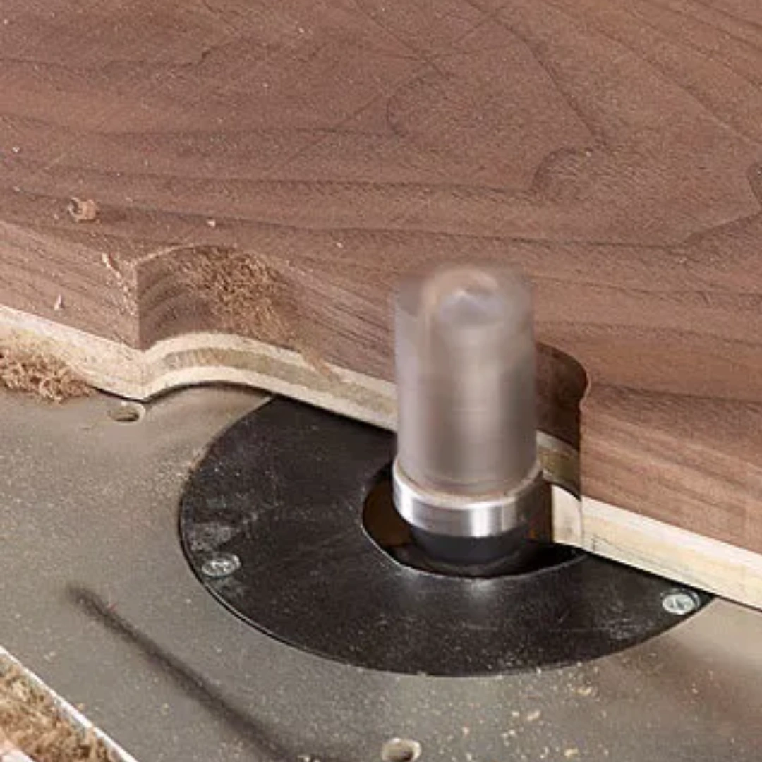 Template routing on a router table, with a bearing-guided bit following a curved wooden template to shape a smooth, matching edge.