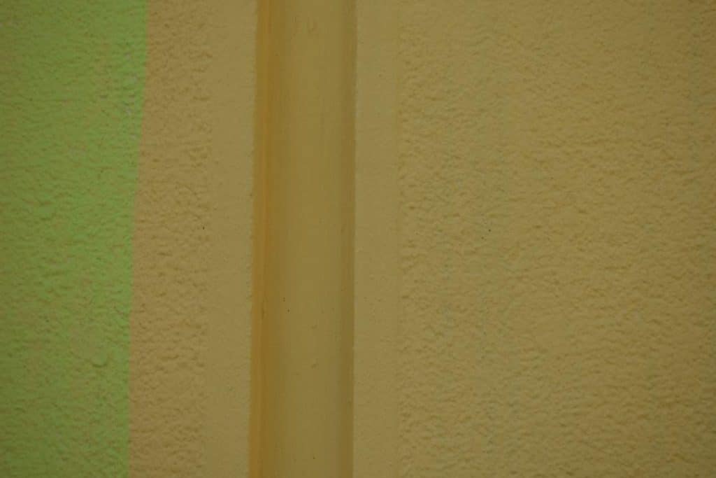 Beige and green textured wall with vertical cylindrical element