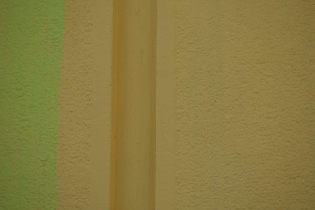 Beige and green textured wall with vertical cylindrical element