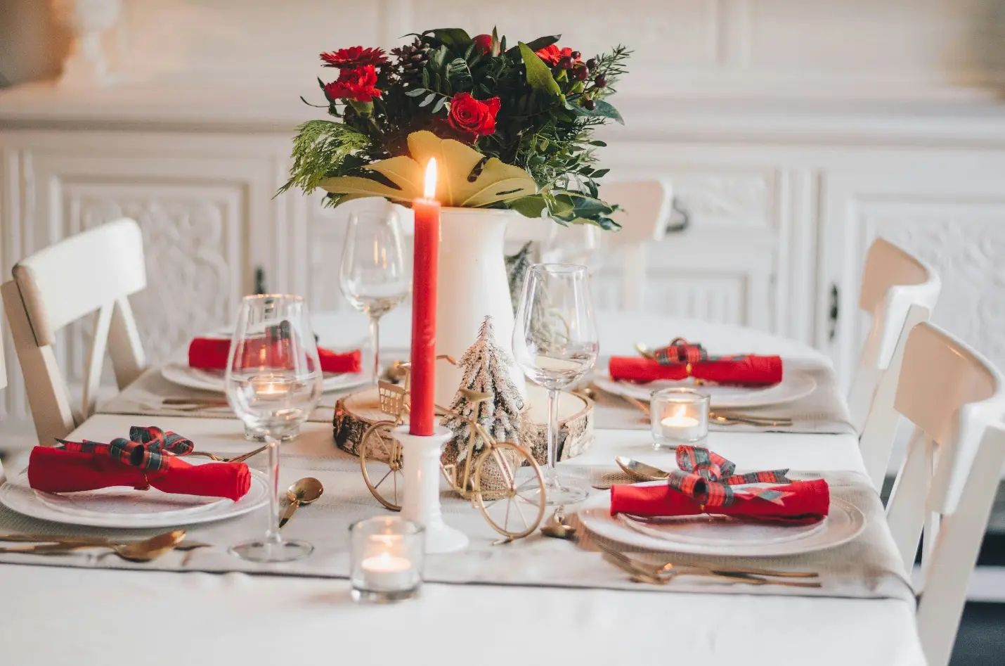 Festive dining table setting with red candles and floral centerpiece in cozy indoor space
